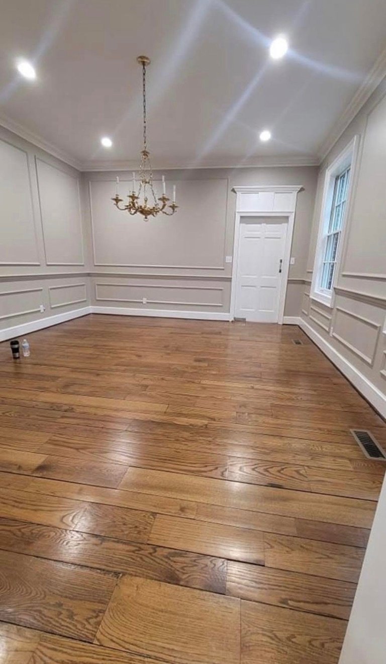 Empty room with white wainscoting walls, hardwood flooring, bronze chandelier, white door, and recessed ceiling lights
