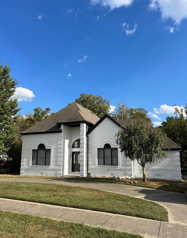 White modern house with peaked roof, arched windows, and manicured lawn under clear blue sky