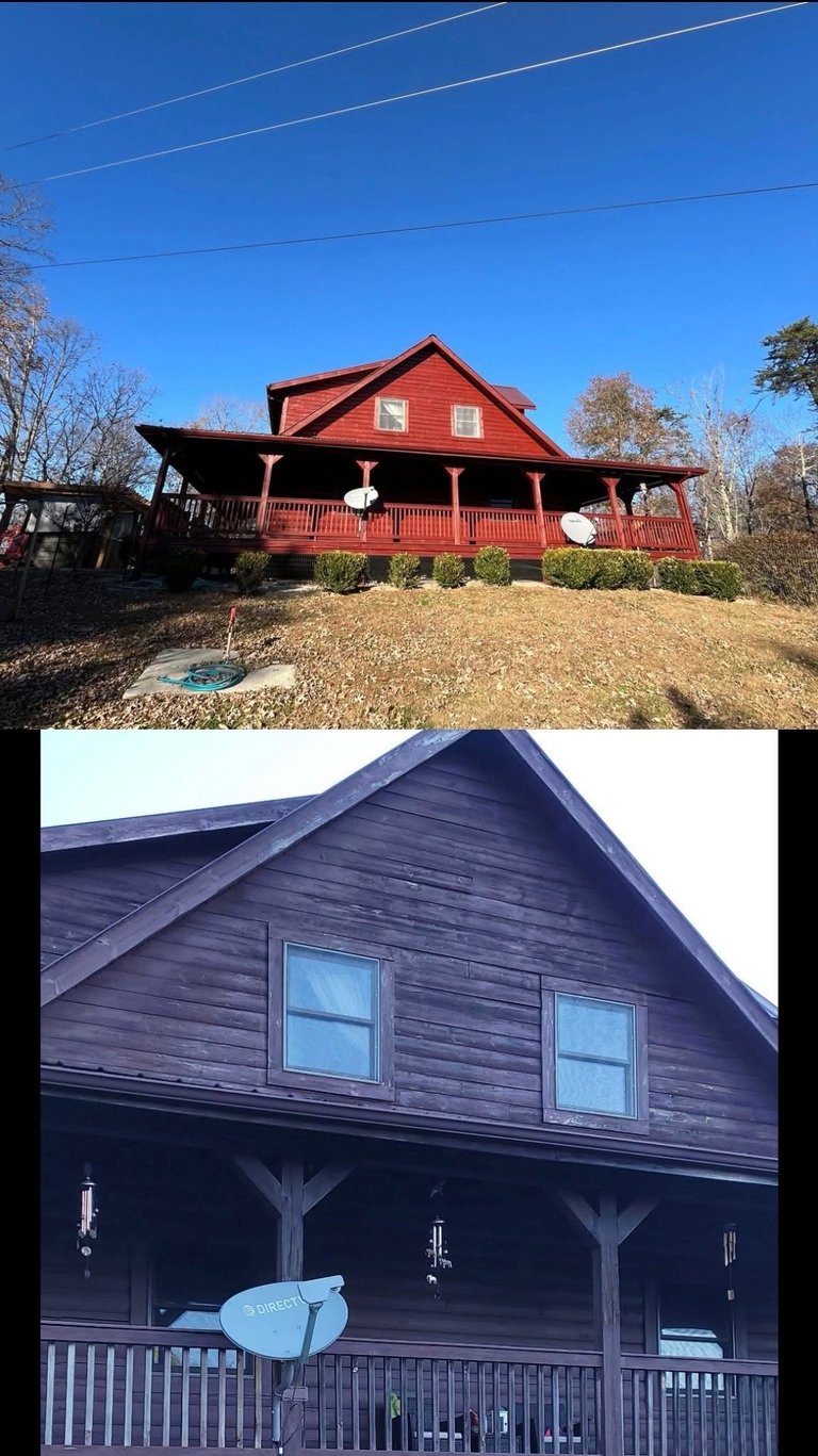 Red farmhouse with large porch under clear blue sky, surrounded by bare trees and brown grass